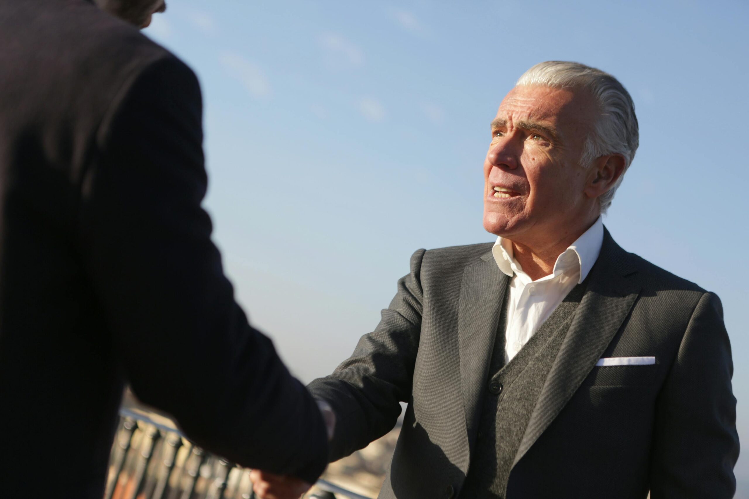 abogado y contra parte dandose la mano despues de lograr una conciliación